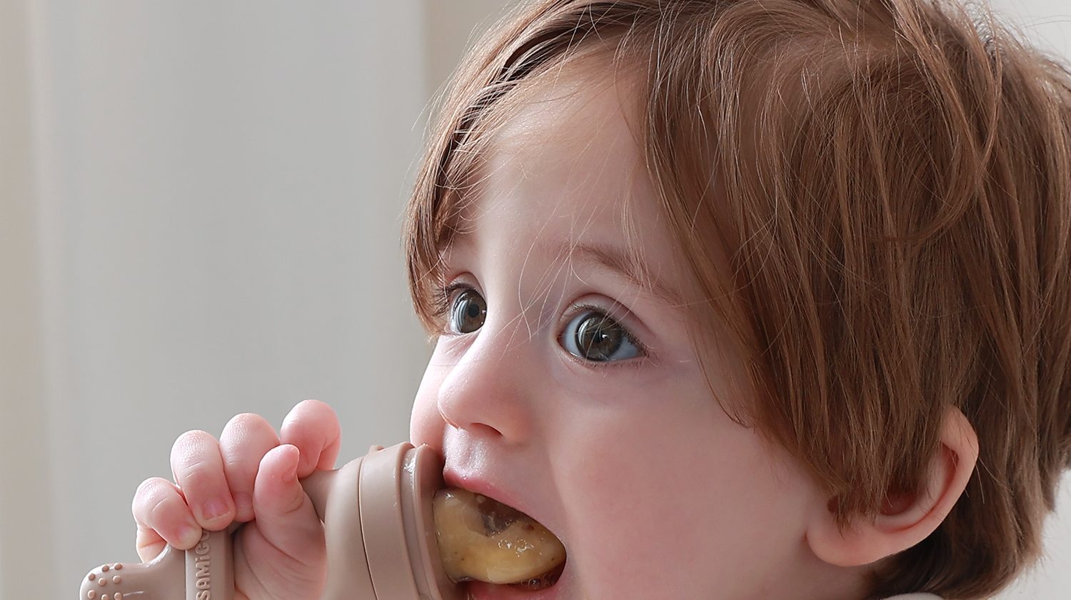 Toddler self feeding with a SAMiGO silicone fruit feeder